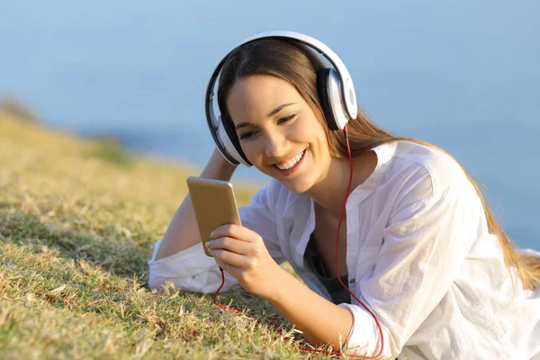 Flicka som lyssnar på musik titta på smartphone innehåll — Stockfoto