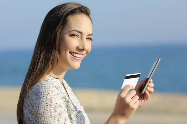 Chica sosteniendo una tarjeta de crédito y teléfono mirando a la cámara — Foto de Stock