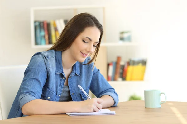 Menina escrevendo em um caderno em casa — Fotografia de Stock