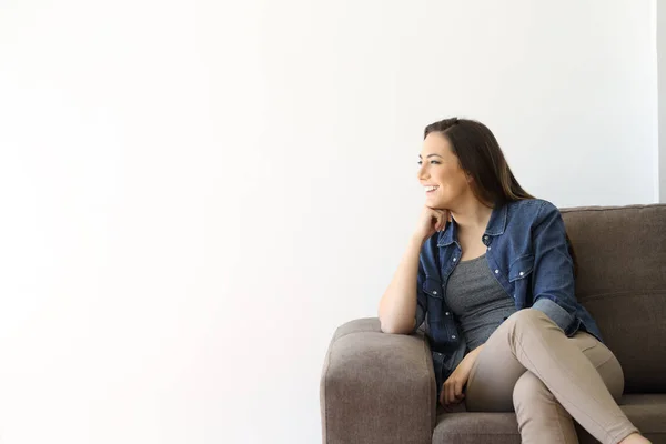Щаслива самотня жінка, дивлячись на сторону сидячи на дивані — стокове фото