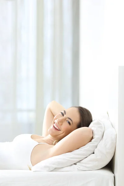 Mujer relajada mirando la cámara en la cama — Foto de Stock