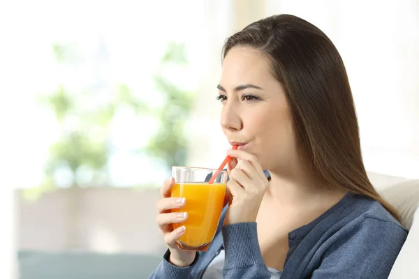 Mujer seria bebiendo jugo de naranja con una pajita — Foto de Stock
