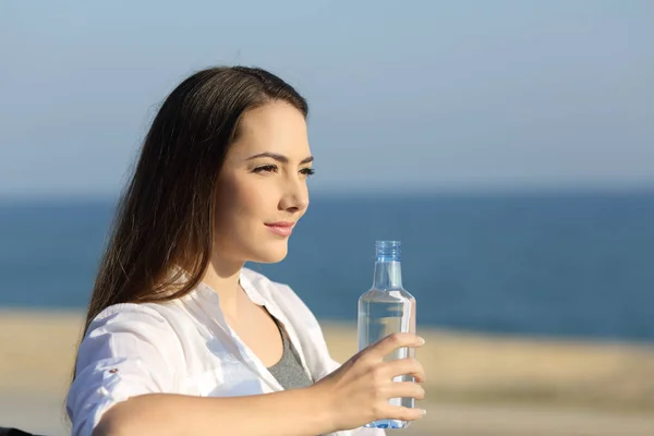 Σοβαρή γυναίκα, κρατώντας ένα μπουκάλι νερό στην παραλία — Φωτογραφία Αρχείου