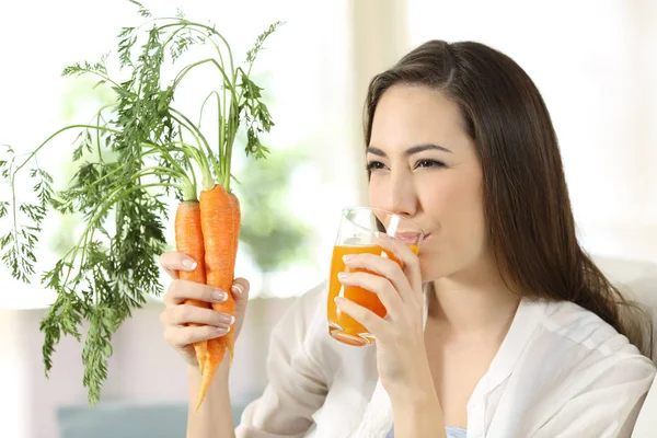 Woman drinking carrot juice at home — Stock Photo, Image