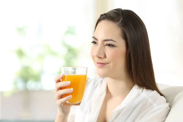 Mulher segurando um copo de suco de laranja em casa — Fotografia de Stock