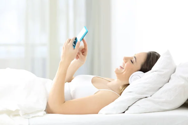 Женщина слушает музыку, лежащую на кровати — стоковое фото