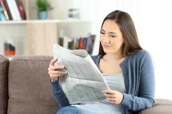 Mulher lendo um jornal sentado em um sofá — Fotografia de Stock