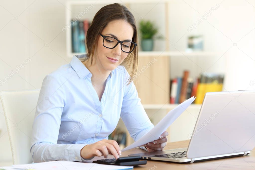 Woman calculating with a calculator at home