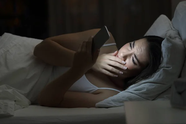 Wanita yang khawatir menggunakan ponsel pintar di tempat tidur di malam hari — Stok Foto