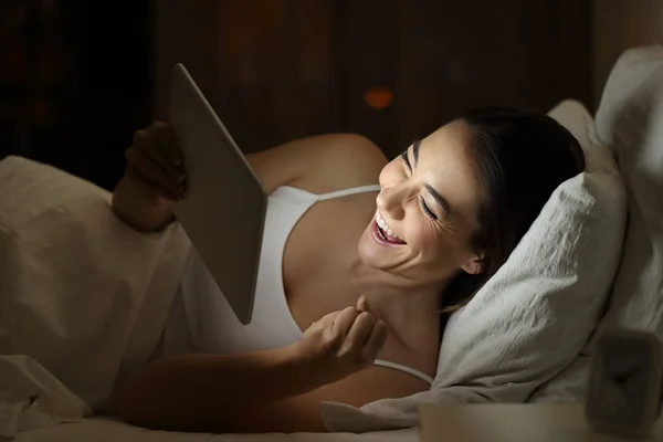 Захоплена жінка використовує планшет на ліжку вночі — стокове фото