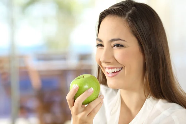 Lycklig kvinna som håller ett äpple som tittar bort — Stockfoto