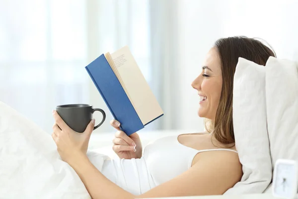 Osoba czytająca książkę leżąc na łóżku — Zdjęcie stockowe