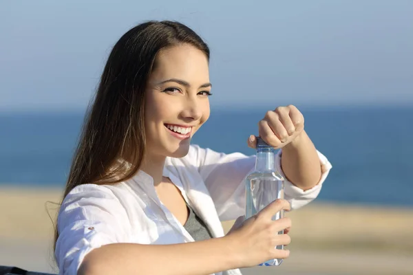 Женщина, открывающая бутылку воды, смотрит в камеру — стоковое фото
