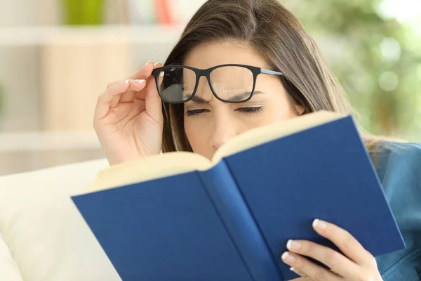 Mulher que sofre de fadiga ocular lendo um livro — Fotografia de Stock
