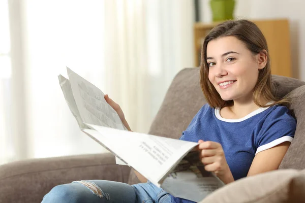 Adolescente che legge un giornale guardando la fotocamera a casa — Foto Stock