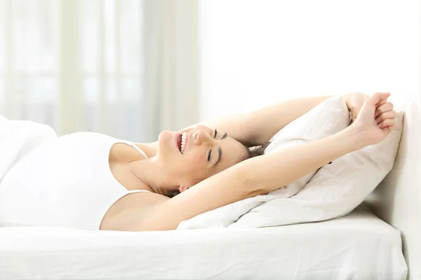 Mulher feliz acordando esticando os braços em uma cama — Fotografia de Stock