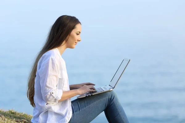 Mulher relaxada escrevendo em um laptop na praia — Fotografia de Stock