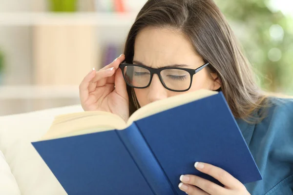 Kobieta cierpi zmęczenie oczu czytając książkę z okularów — Zdjęcie stockowe