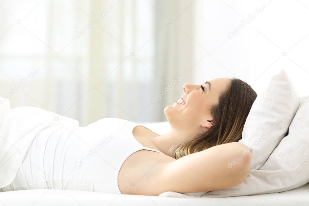 Happy woman resting lying on a bed looking up