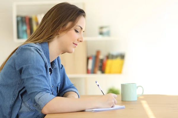 Mulher relaxada escrevendo uma nota em um caderno — Fotografia de Stock