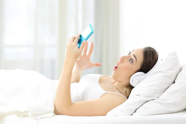 Mujer sorprendida escuchando música en una cama —  Fotos de Stock