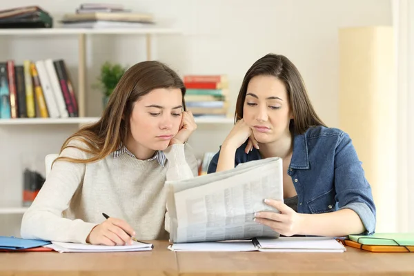 Два скучающих студента читают газету — стоковое фото