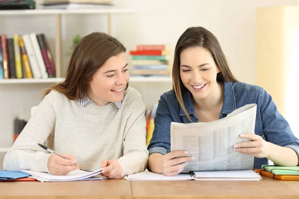 Zwei glückliche Studenten beim Lesen einer Zeitung — Stockfoto