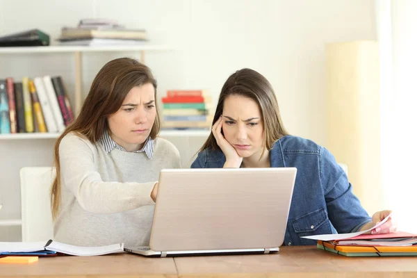 Dois estudantes preocupados consultando informações on-line em um laptop — Fotografia de Stock