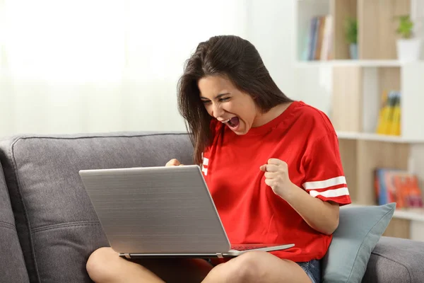 Adolescente animado recebendo boas notícias on-line em casa — Fotografia de Stock