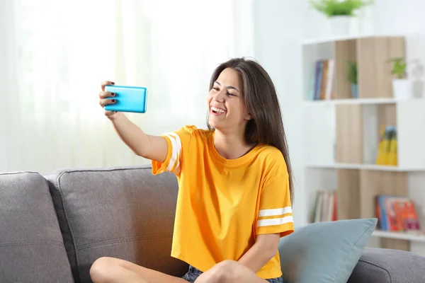 Adolescente feliz tomando selfies sentado em um sofá — Fotografia de Stock