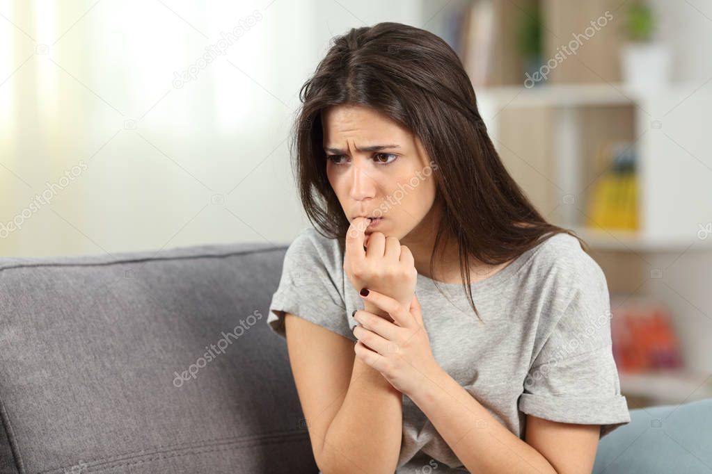 Nervous teen biting nails alone at home