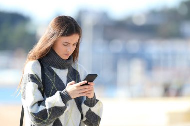 Ciddi kız kışın cep telefonu kullanıyor.