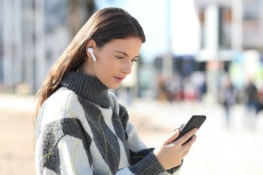 Kablosuz kulaklıklı ciddi bir kız müzik dinliyor.