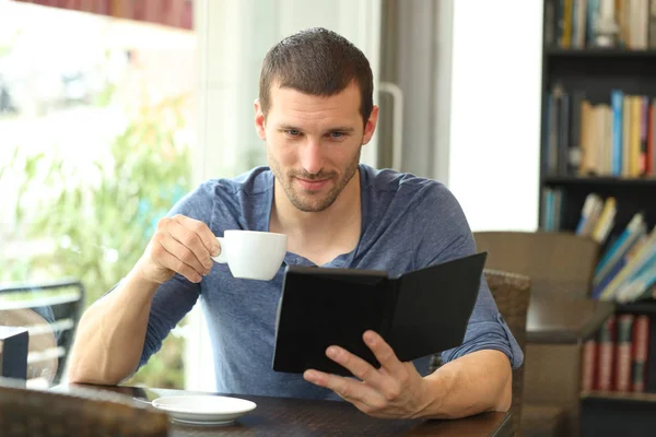 Homem sério lendo um ebook em um café — Fotografia de Stock