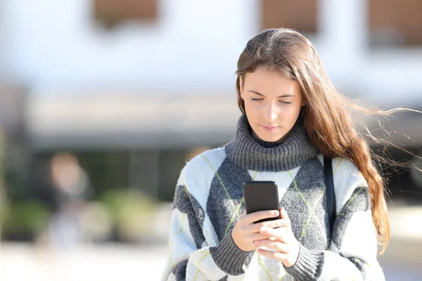 Девушка в свитере с помощью мобильного телефона осенью — стоковое фото