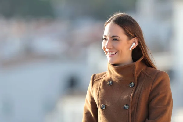 Happy girl wearing wireless earphones listening to music — Stock fotografie