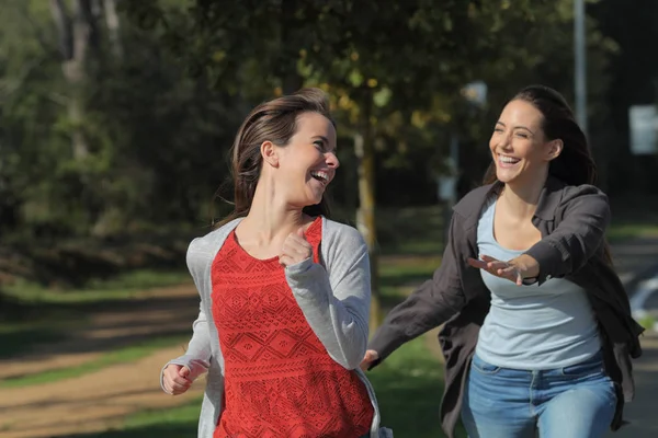 Два счастливых друга шутят, гоняясь в парке — стоковое фото