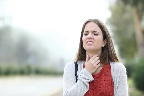 Ill vrouw lijden keel zere wandelingen in een park een mistige dag — Stockfoto