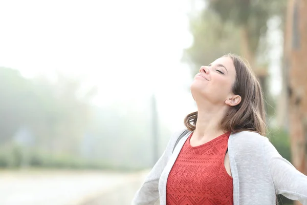 Nöjd kvinna andas frisk luft en dimmig dag — Stockfoto