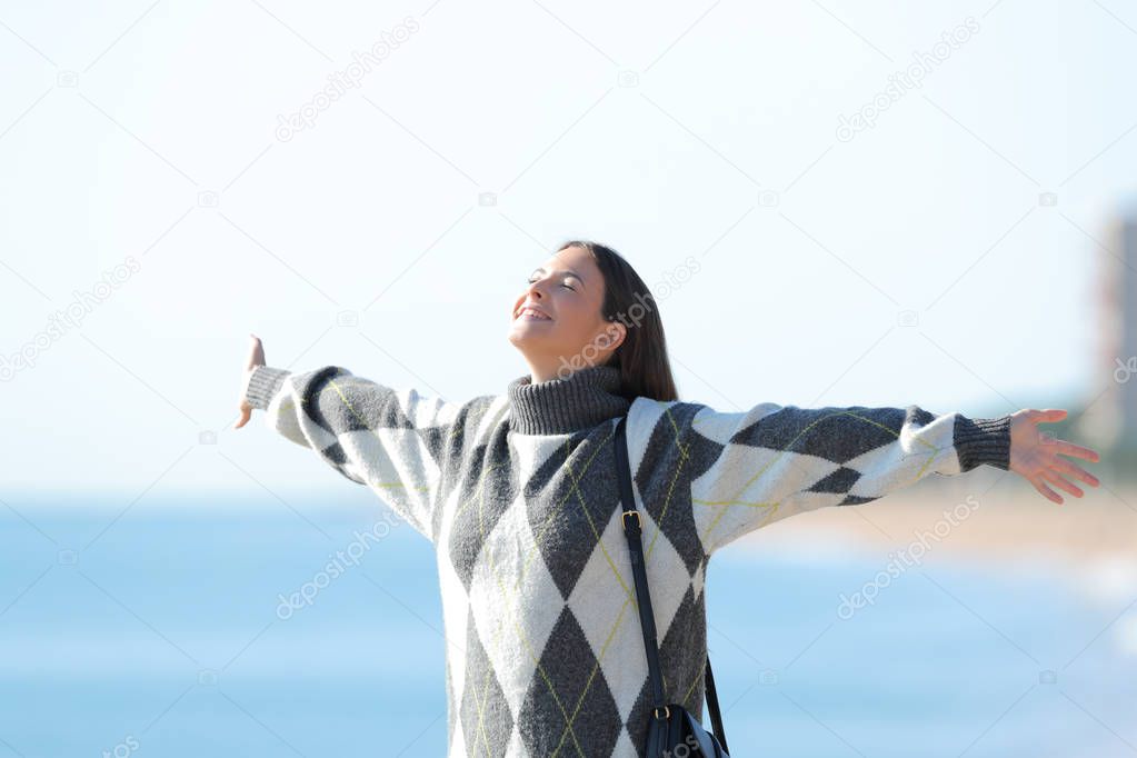 Happy girl with jersey stretching arms on the beach