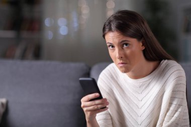 Elinde telefon olan şüpheli bir kadın gece kameraya bakıyor.