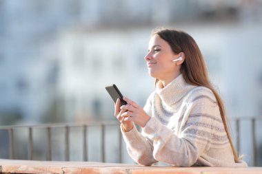 Rahat kadın balkonda müzik dinliyor.