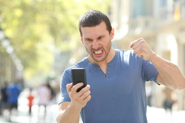 Hombre enojado revisando el teléfono inteligente estrellado en la calle — Foto de Stock