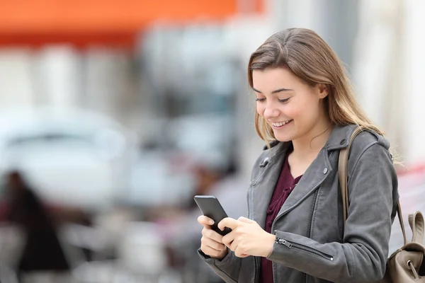 Feliz adolescente mensagens de texto no celular andando na rua — Fotografia de Stock