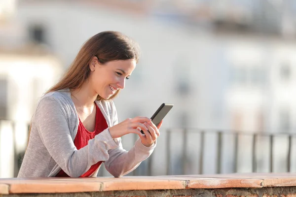 Happy girl za pomocą telefonu komórkowego na balkonie — Zdjęcie stockowe