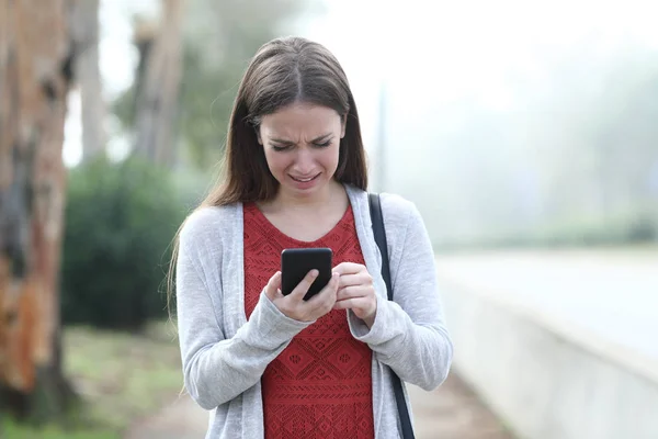 Сумна жінка плаче, ходячи по мобільному телефону в парку — стокове фото