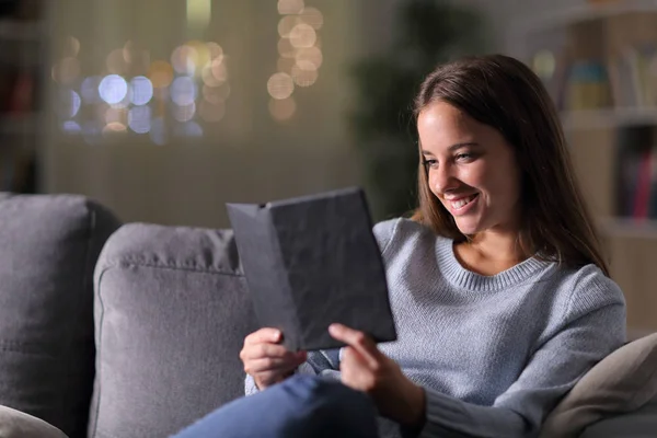 Mulher feliz lendo um ebook na noite em casa — Fotografia de Stock