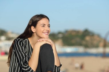 Kumsalda manzaralar seyreden mutlu bir kız.