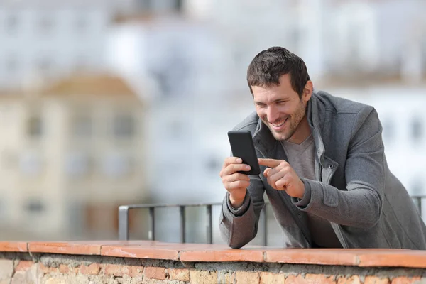 Homem adulto feliz no inverno usando telefone celular em uma varanda — Fotografia de Stock