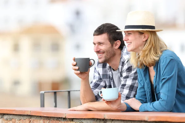 Coppia di turisti che beve caffè e distoglie lo sguardo da un balcone — Foto Stock